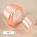 Roll of peach ribbon on a wooden surface with text indicating length and color.