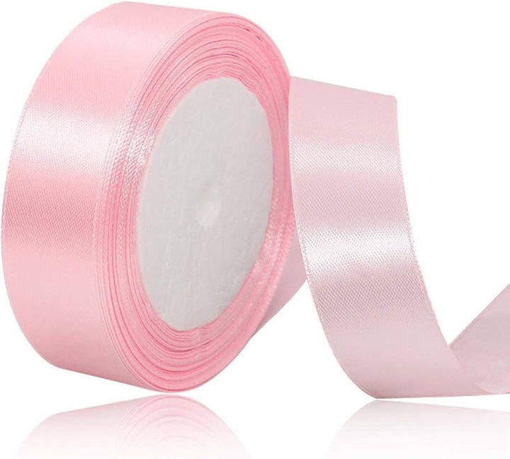 Roll of pink satin ribbon on a white background